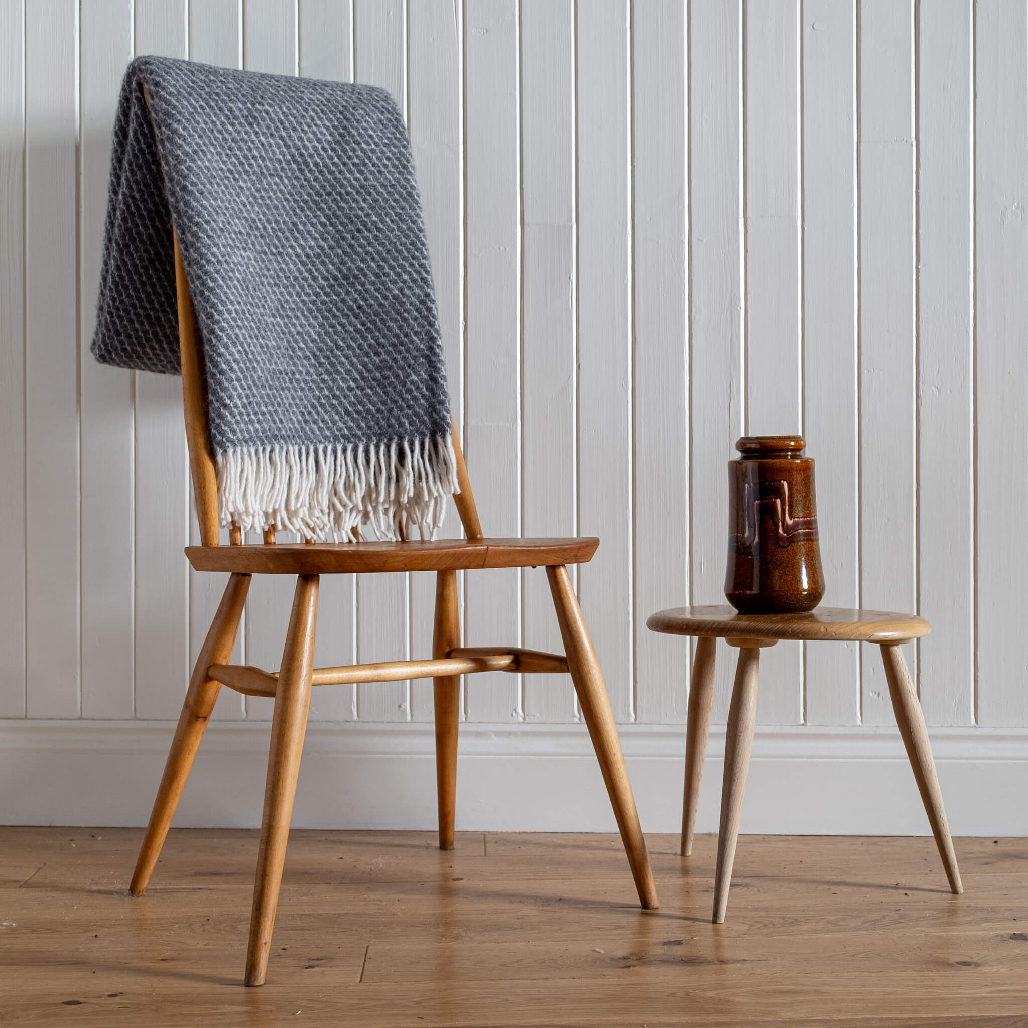 Honeycomb Wool Blanket – Grey, folded on the back of a chair with vintage vase