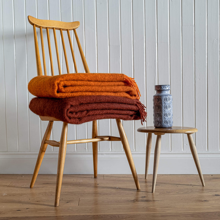 Gotland Wool Blanket – Rust & Orange folded on a chair